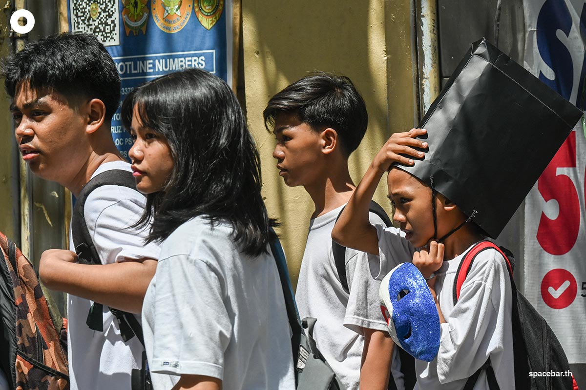 นักเรียนหญิงคนหนึ่งนำถุงกระดาษมาสวมบนหัวเพื่อกันแดด ขณะออกจากโรงเรียนในกรุงมะนิลาเมื่อวันที่ 3 มีนาคม 2025 (Photo by Jam STA ROSA / AFP)
