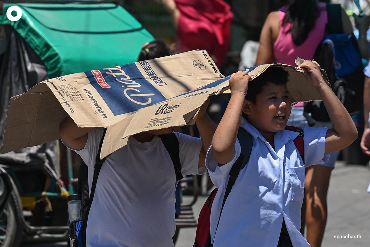 นักเรียนชาย 2 คนใช้กระดาษแข็งจากกล่องกระดาษบังแดดในช่วงวันที่อากาศร้อนในกรุงมะนิลาเมื่อวันที่ 2 เมษายน 2024 (Photo by JAM STA ROSA / AFP) 