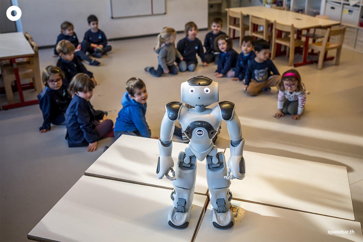 เด็กอนุบาลชาวสวิสกำลังจ้องมอง ‘นาโอะ’ (robot Nao) หุ่นยนต์เพื่อการศึกษาและการสื่อสารโต้ตอบ ที่ศูนย์เด็กก่อนวัยเรียน ‘ลา นองออสแฟร์’ ในวิทยาเขตของสถาบันเทคโนโลยีแห่งสหพันธ์สวิส เมืองโลซาน สวิตเซอร์แลนด์ (Photo by Fabrice COFFRINI / AFP)